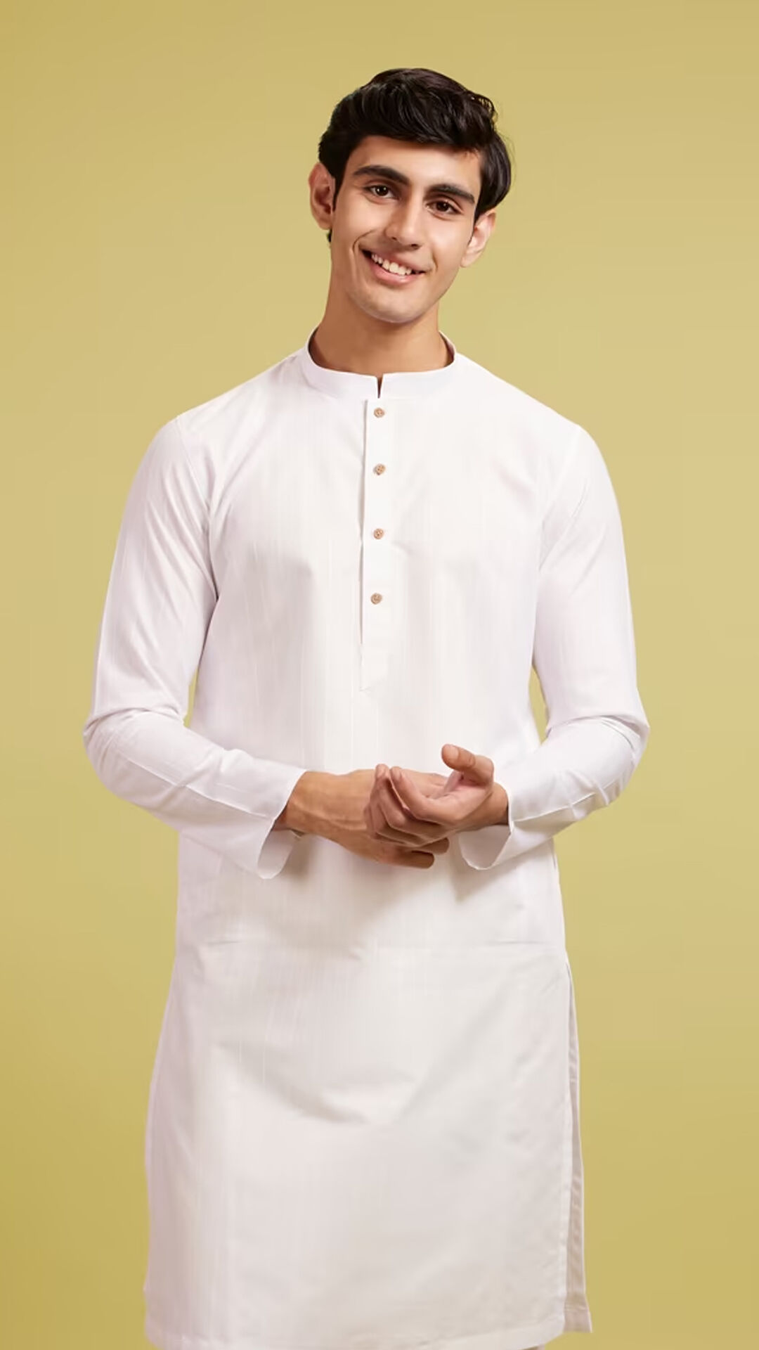 Smiling man wearing a white chikankari kurta and sunglasses, adjusting his sleeve while posing confidently against a bright blue background, blending traditional elegance with modern flair.